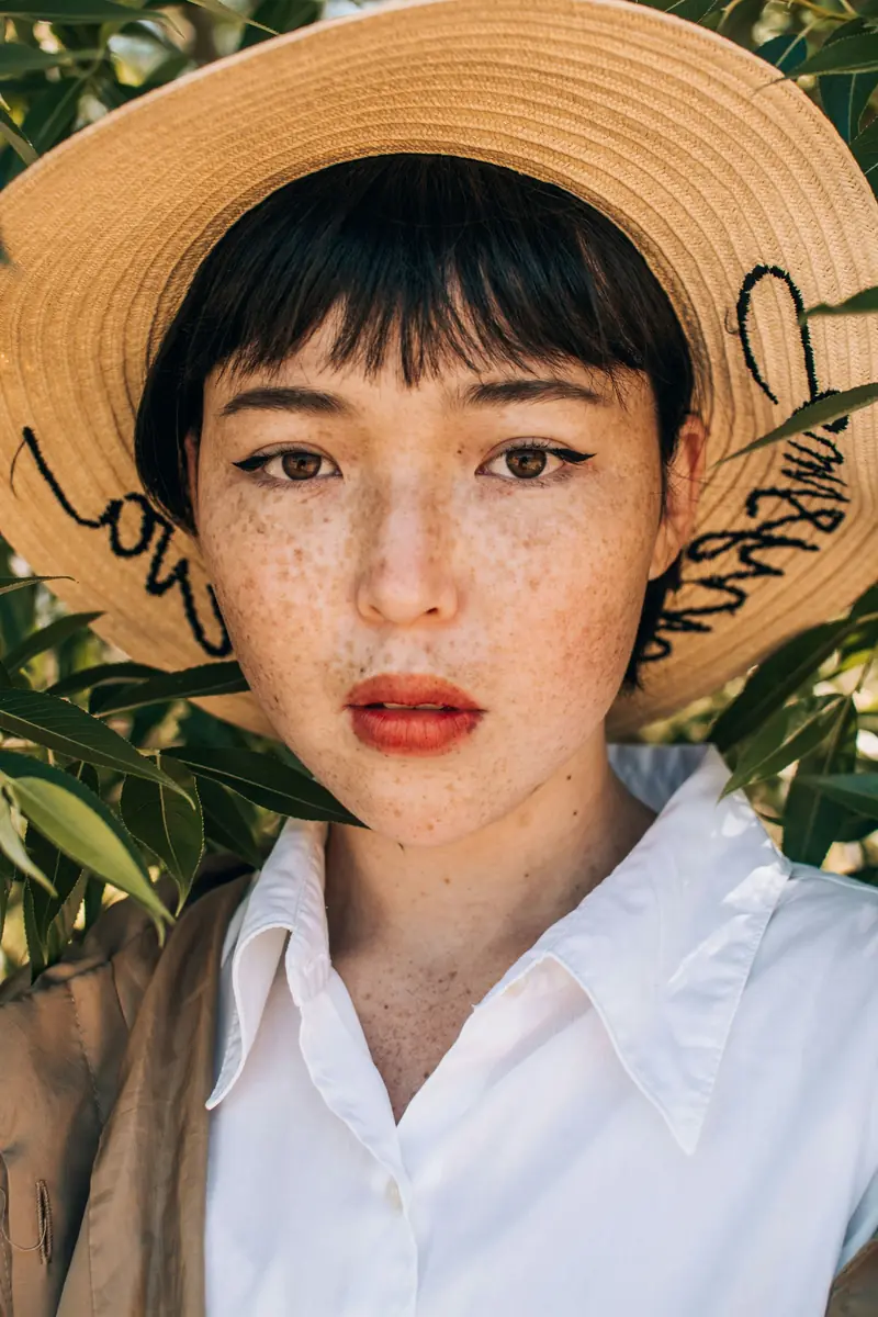 A woman with freckles wearing a straw hat