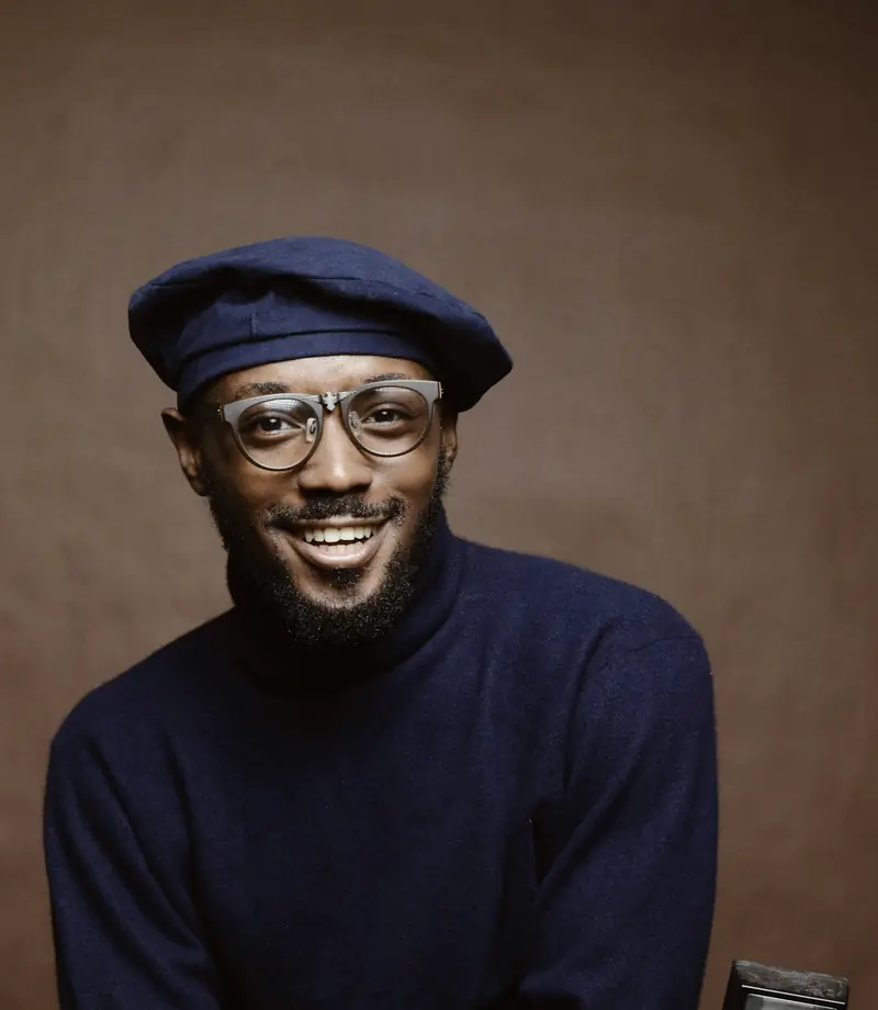 A smiling man in glasses, a beret and a navy sweater